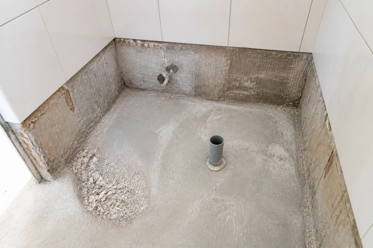 Salle de bain en cours de travaux avec ancien bac à douche déposé et sol protégé