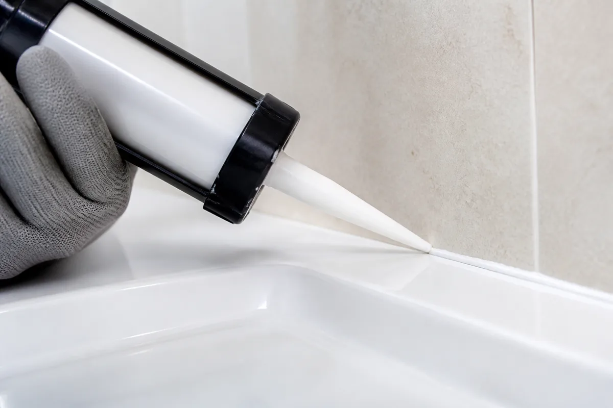 Application d&rsquo;un joint silicone sanitaire au pistolet le long d&rsquo;un receveur de douche